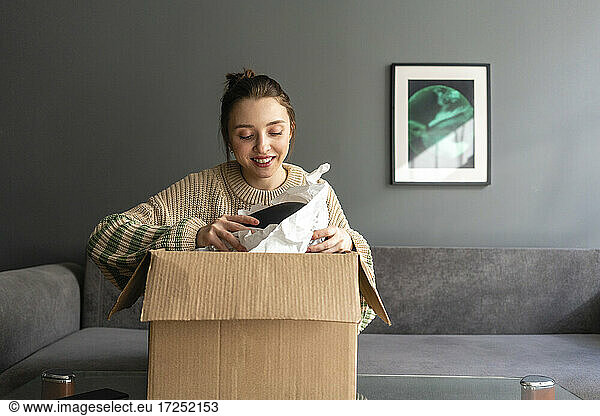 Lächelnde Frau beim Auspacken eines Kartons zu Hause