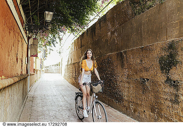Lächelnde Frau beim Radfahren in einer Gasse