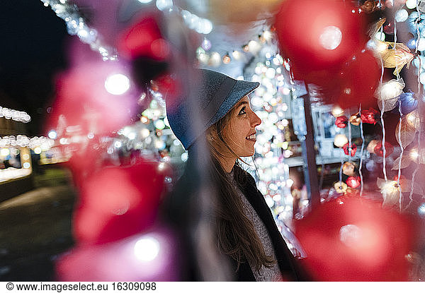 Lächelnde Frau  die einen Stand auf einem nächtlichen Rummelplatz beobachtet