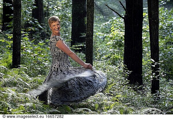 Lächelnde Frau  die sich vor Freude im Wald dreht - Brevard  North Carolina  USA.