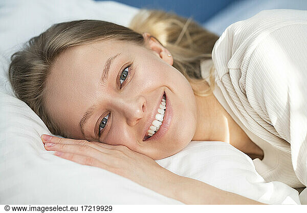 Lächelnde Frau  die zu Hause auf einem Kopfkissen liegt