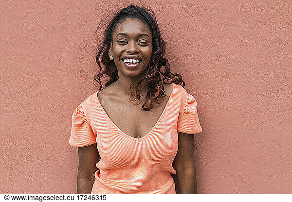 Lächelnde Frau in Freizeitkleidung an der Wand