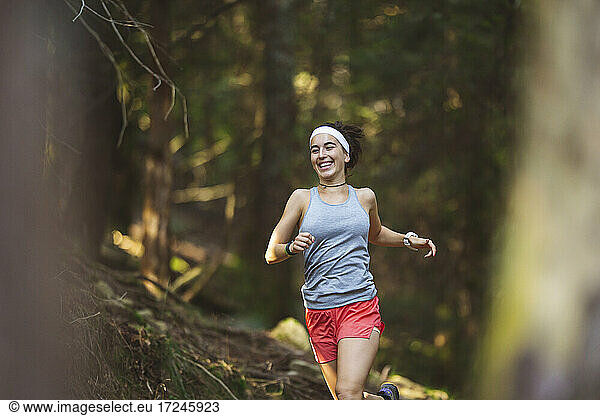 Lächelnde Frau in Sportkleidung beim Laufen im Wald