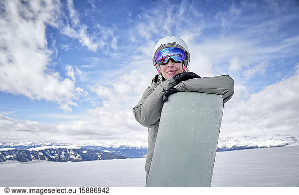 Lächelnde Frau lehnt auf Snowboard