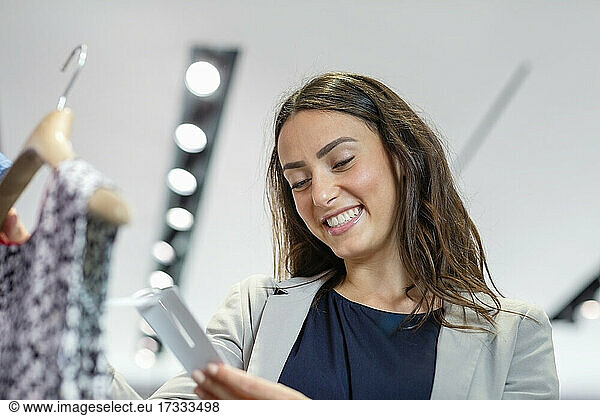Lächelnde Frau mit Blick auf das Preisschild in einer Boutique
