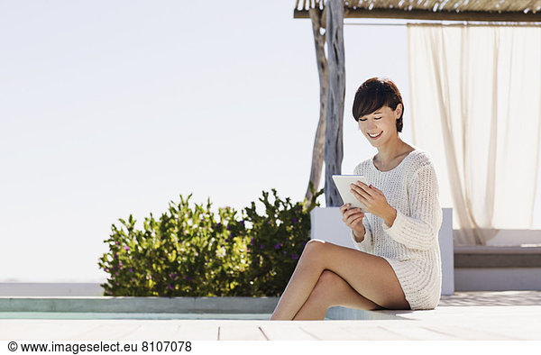 Lächelnde Frau mit digitalem Tablett am Pool