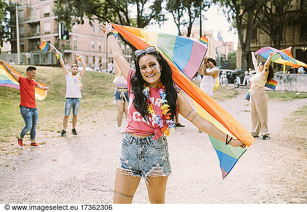 Lächelnde Frau mit Regenbogenfahne bei Pride-Event im Park