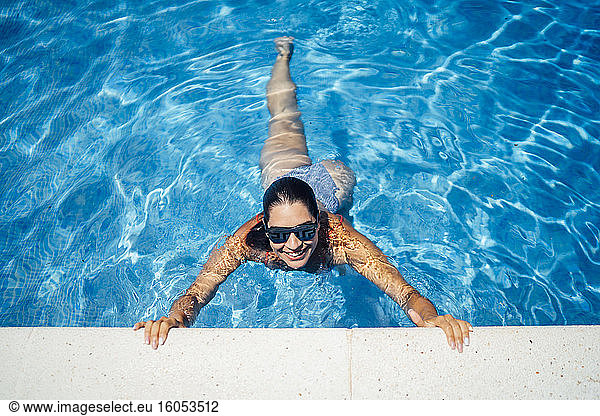 Lächelnde Frau mit Sonnenbrille am Pool