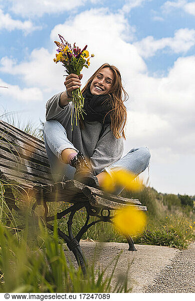 Lächelnde Frau sitzt auf einer Bank in der Natur