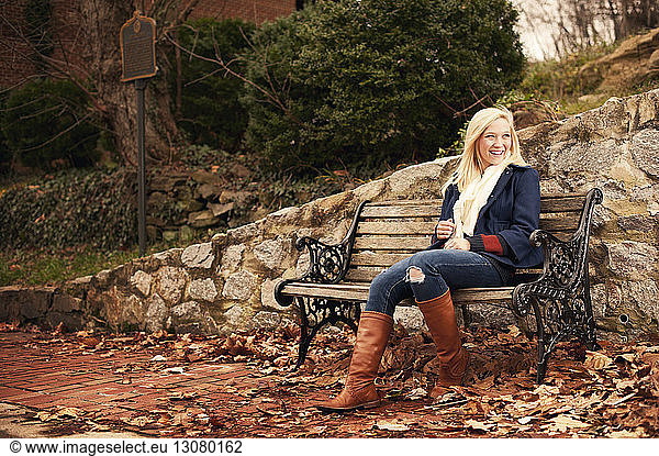 Lächelnde Frau sitzt im Winter auf einer Parkbank