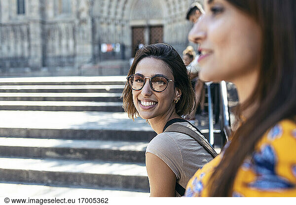 Lächelnde Frau sitzt mit einem Freund auf dem Platz der Kathedrale von Barcelona in Barcelona  Katalonien  Spanien