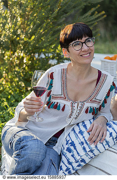 Lächelnde Frau trinkt Rotwein auf dem Land