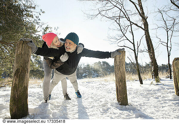 Lächelnde Frau umarmt Mann beim Sport im Schnee