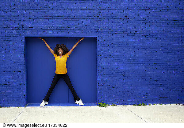 Lächelnde Frau vor blauer Backsteinmauer stehend