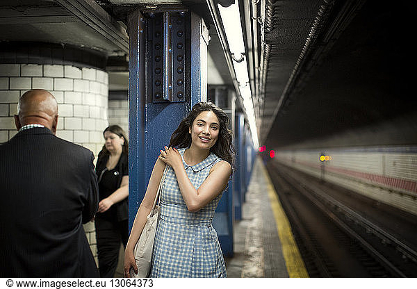 Lächelnde Frau wartet in der U-Bahn auf den Zug