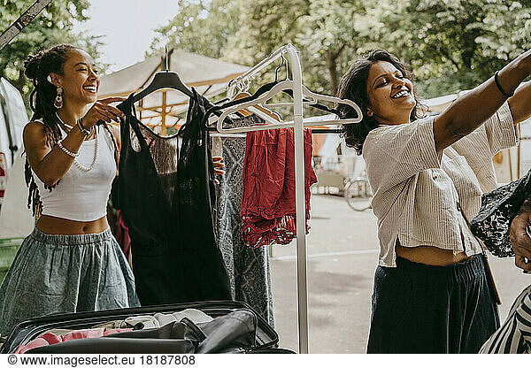 Lächelnde Frauen  die auf einem Flohmarkt ein Kleid kaufen