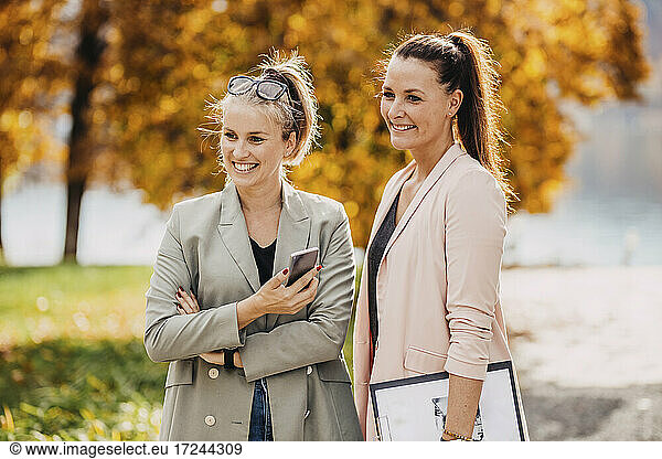 Lächelnde Frauen in eleganter Freizeitkleidung stehen zusammen im Garten