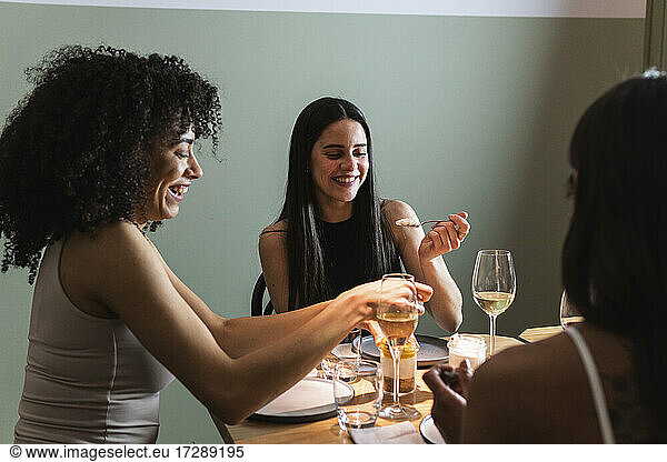 Lächelnde Freunde beim gemeinsamen Essen und Trinken im Restaurant