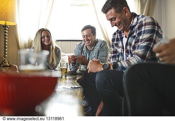 Lächelnde Freunde beim Kartenspiel beim geselligen Beisammensein zu Hause