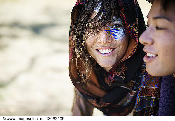 Lächelnde Freunde mit Gesichtsbemalung sprechen während der traditionellen Veranstaltung