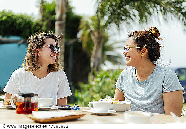 Lächelnde Freundinnen  die sich beim Frühstück gegenseitig anschauen
