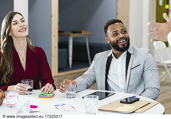 Lächelnde Geschäftsleute  die einen Kollegen in einer Besprechung ansehen