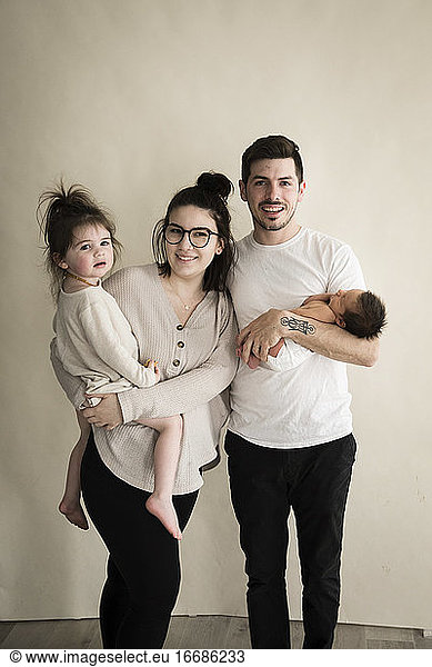 Lächelnde Hipster-Millennial-Familie mit Kleinkind und Neugeborenem