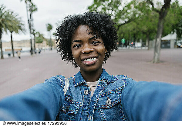 Lächelnde junge Frau mit Afrofrisur macht ein Selfie