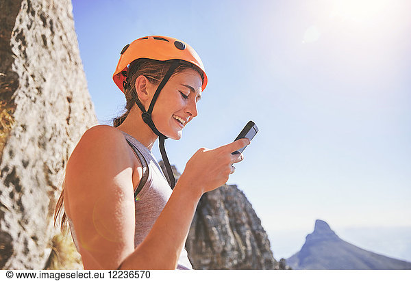 Lächelnde Klettererin mit Smartphone