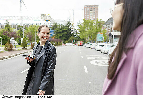 Lächelnde Kollegen  die sich beim Gehen auf der Straße ansehen