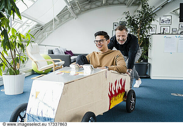 Lächelnde Kollegen spielen mit Spielzeugauto im Büro