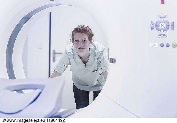 Lächelnde Krankenschwester vor CAT-Scan-Maschine