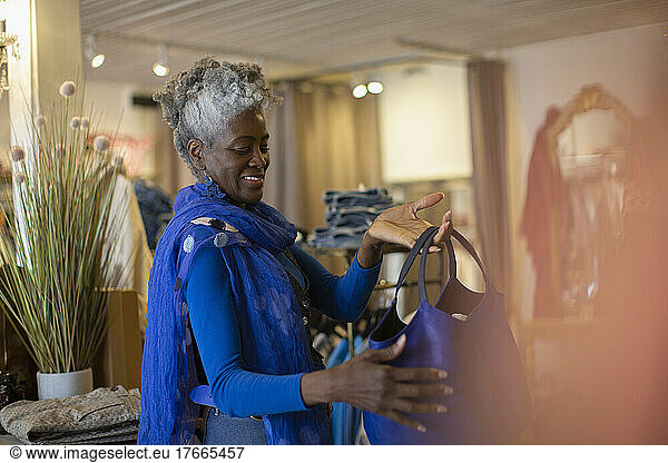 Lächelnde ältere Frau in Blau betrachtet eine Handtasche in einem Geschäft