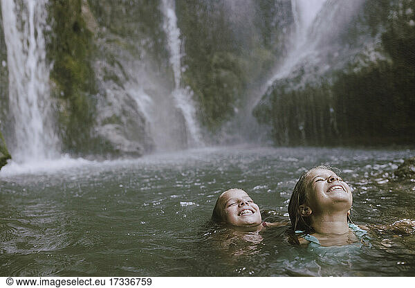 Lächelnde Mädchen mit geschlossenen Augen haben Spaß im Wasser