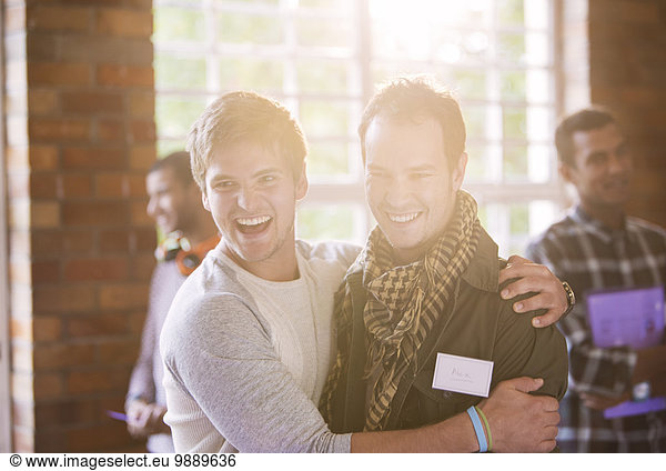 Lächelnde Männer umarmen sich beim Seminar