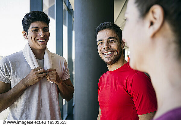 Lächelnde männliche Athleten im Gespräch mit einer Frau in einer Turnhalle während der Pause