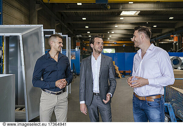 Lächelnde männliche Fachleute bei einer Diskussion in einer Fabrik