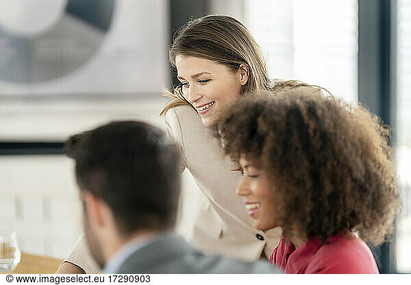 Lächelnde männliche und weibliche Fachleute  die im Büro diskutieren