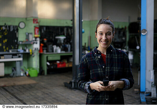 Lächelnde Mechanikerin mit Ausrüstung in der Werkstatt