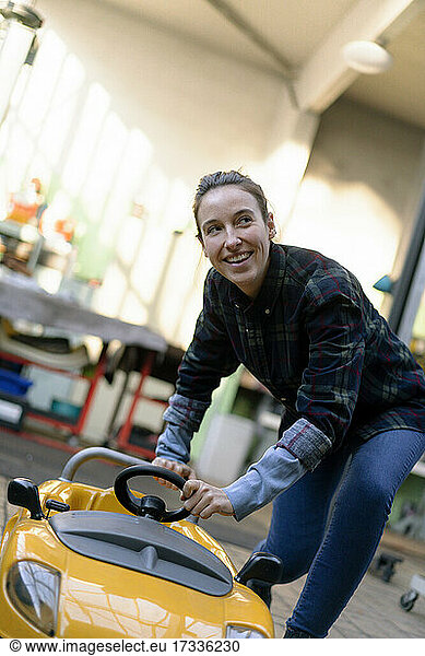 Lächelnde Mechanikerin mit Spielzeugauto in der Werkstatt