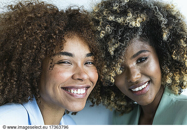 Lächelnde multiethnische Kolleginnen mit lockigem Haar