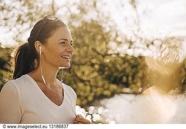 Lächelnde reife Frau spricht im Sommerurlaub über Kopfhörer