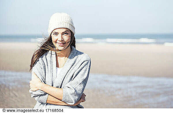 Lächelnde schöne Frau in Strickjacke Pullover am Strand an einem sonnigen Tag