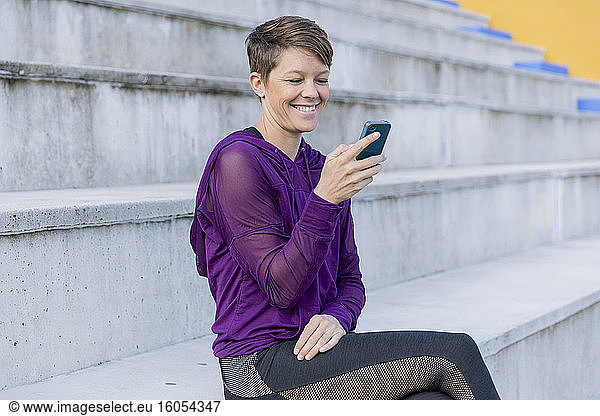Lächelnde  sportliche Frau mit Smartphone