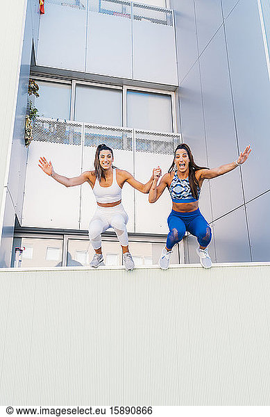 Lächelnde sportliche Zwillinge springen von einer Wand