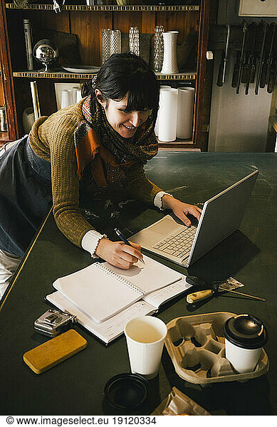 Lächelnde Unternehmerin arbeitet an einem Laptop in einem Upcycling-Laden
