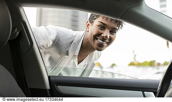 Lächelnde weibliche Fachkraft schaut durch ein Autofenster