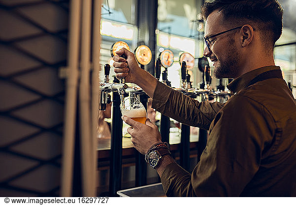 Lächelnder Barkeeper zapft Bier in einer Kneipe