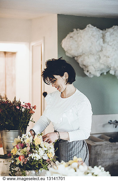 Lächelnder Florist arrangiert Blumen im Geschäft