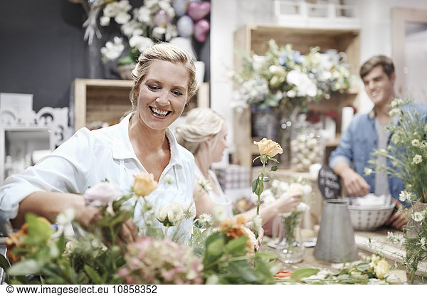 Lächelnder Florist arrangiert Blumenstrauß im Blumenladen